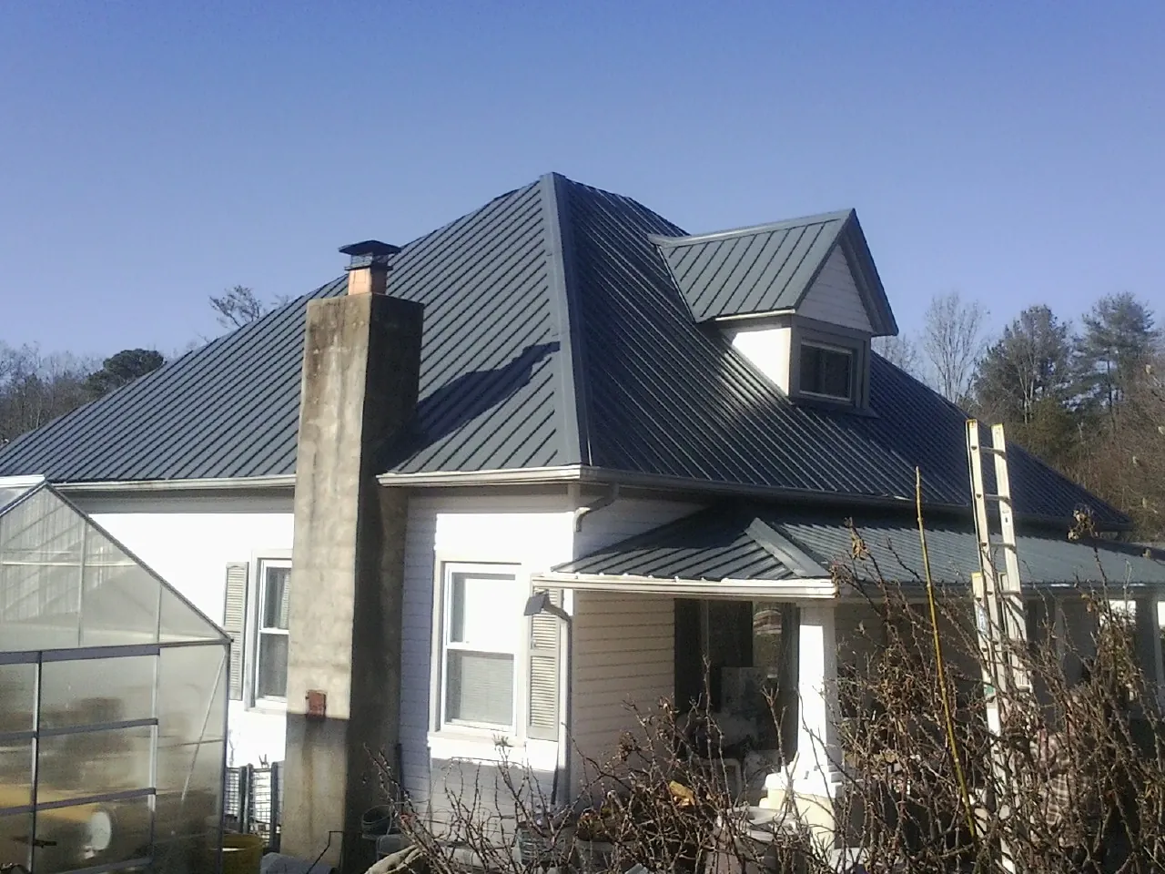 Dark blue standing seam metal roof on a white farmhouse with dormer — Slate & Tile Roof Repair by Roofing Brothers in Michigantown