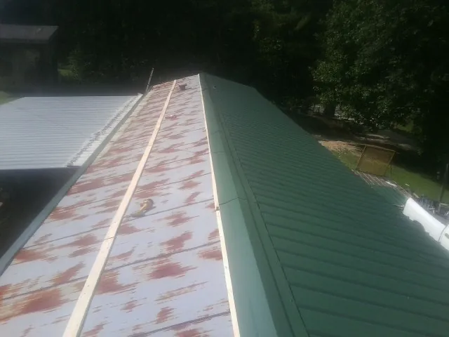 Old rusted panels beside newly installed green metal roofing — Wind Damage Roof Repair by Roofing Brothers in Michigantown