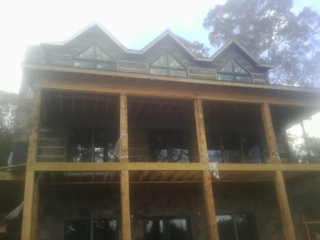 Dormers and porch framing on a large log home under construction — Roof Coating work by our crew in Michigantown