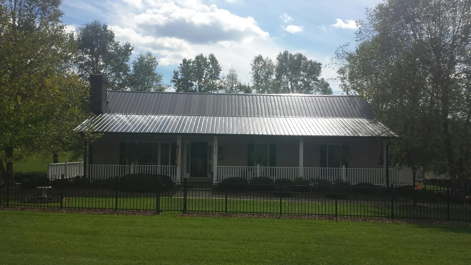 Gray metal roof on a brick ranch with a full width front porch — Gutter Guard Installation work by our crew in Michigantown