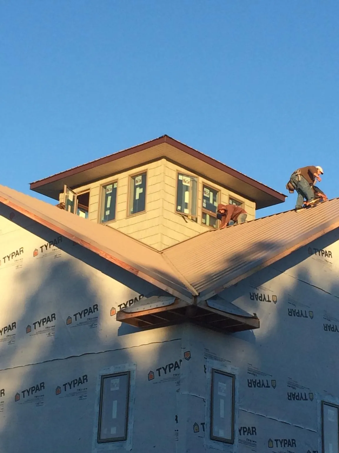 Roofers working around a rooftop cupola on a new metal roof at sunset — Roof Waterproofing in Michigantown by Roofing Brothers